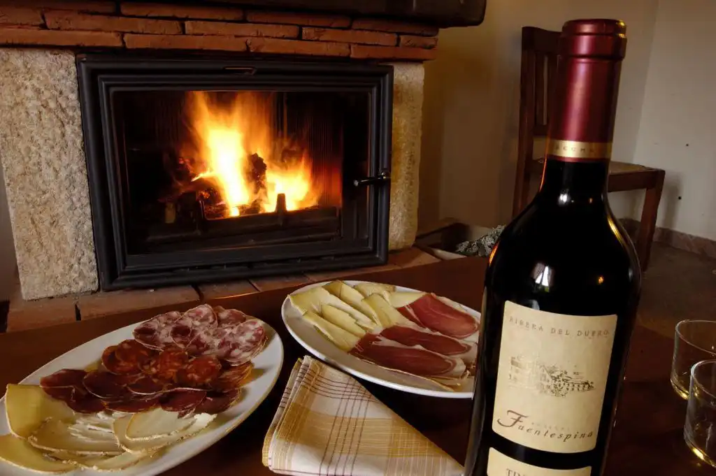 Mesa con embutido, vino y chimenea en La Quinta del Chocolatero